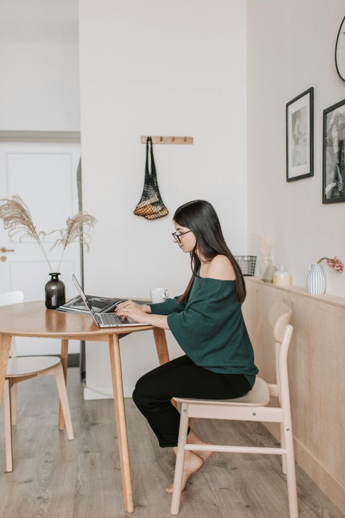 Young woman working from dinning room table home office.