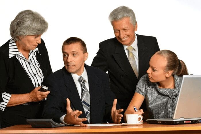 Four colleagues discussing documents around desk