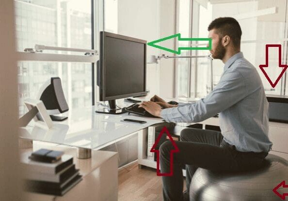 Man slouching on exercise ball at workstation