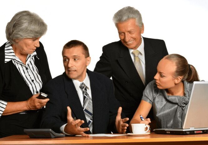 Four colleagues discussing documents around desk