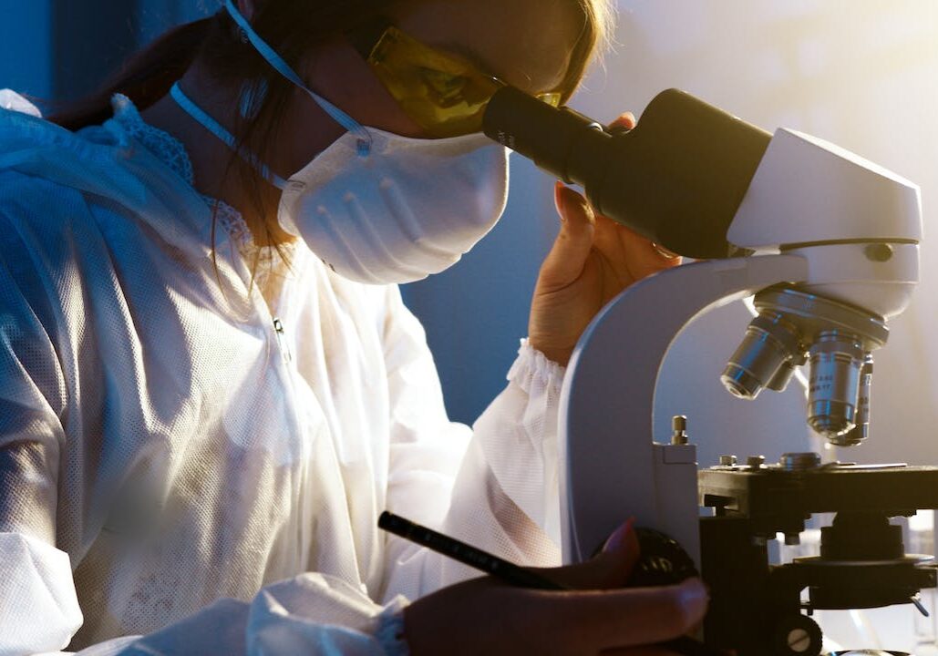 A scientist working at a microscope in a lab with poor forward-head posture